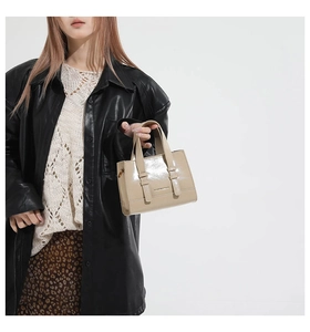Detail of elegant beige patent leather handbag with glossy finish and double handles