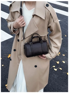 Detail of coffee brown lychee grain leather mini barrel bag with silver hardware on street