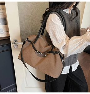 Detail shot of large brown canvas tote bag with black leather straps on model
