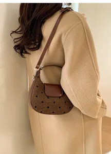 Détail d'un sac demi-lune en tweed marron à pois porté avec un manteau en laine