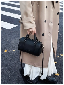 Detail of black pebbled leather Boston bag with gold hardware on a city street