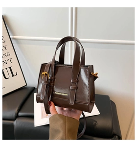 Detail view of dark brown mini square bag with glossy finish and gold fashion logo