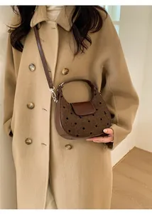 Détail latéral d'un sac hobo en tweed marron à pois avec bandoulière en cuir souple