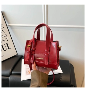 Detail of red patent leather mini crossbody bag with gold hardware and top handles