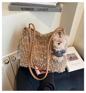 Détail d'un sac cabas en peluche marron avec des anses en cuir et un ours en peluche