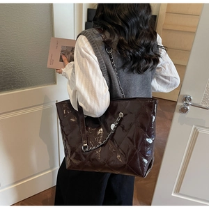 Close-up of quilted coffee brown tote bag with glossy finish and silver chain strap