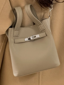 Beige litchi leather bucket handbag with silver lock worn on a camel winter coat