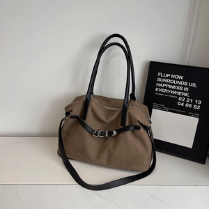 Detail view of brown fabric tote bag with black leather handles and silver metal hardware