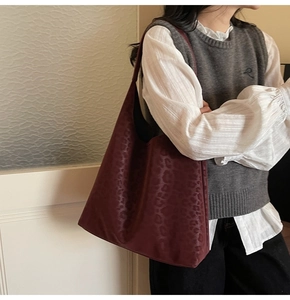 Gros plan d'un sac cabas léopard bordeaux porté avec une chemise blanche et un gilet