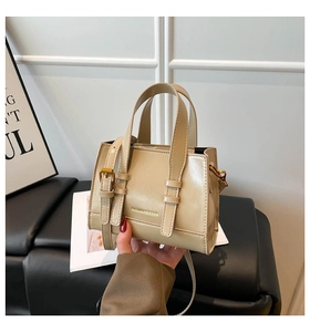 Detail of a chic beige leather crossbody bag with top handles and adjustable strap