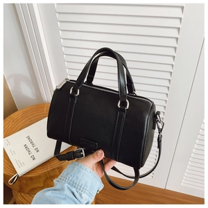 Detail of black pebbled leather Boston bag with silver hardware and adjustable strap