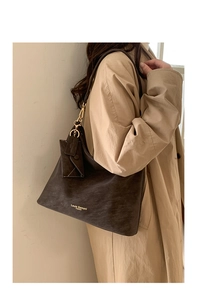 Detail of deep brown leather tote bag with matching pouch and gold hardware on model