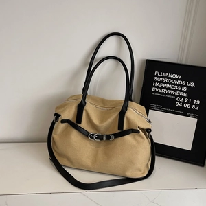 Detail of high-capacity khaki canvas handbag with black leather straps and silver metal buckles