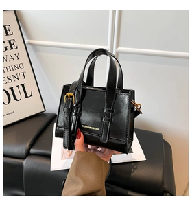 Detail view of the sleek black faux leather handbag with adjustable golden buckle strap