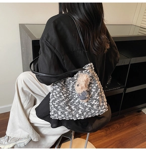 Détail d'un sac cabas en tweed avec bandoulière en cuir et breloque ours en peluche