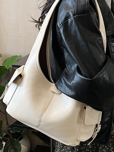 Minimalist beige oversized tote bag in soft matte leather shown in a lifestyle shoulder view