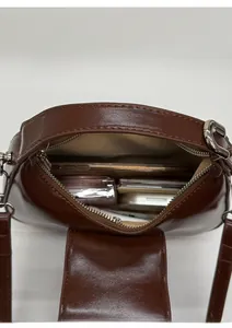 Vue intérieure montrant la capacité du sac demi-lune en cuir marron avec accessoires