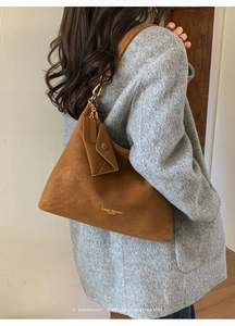Caramel brown suede hobo bag styled with a gray wool coat and matching charm
