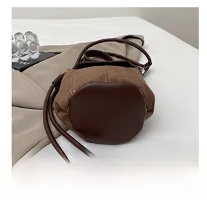 Detail of durable round bottom on brown suede bucket bag with smooth leather stitching