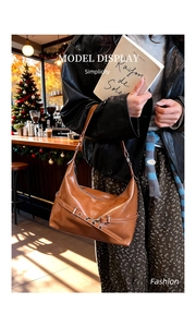 Brown patent leather shoulder bag with silver buckle detail in a cozy cafe setting