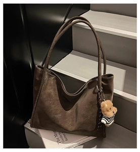 Close-up of retro dark brown suede tote bag featuring a cute striped bear pendant charm