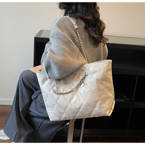 Detail of white quilted tote bag in glossy patent leather with silver chain strap