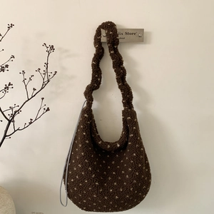 Dettaglio della borsa tote in peluche marrone con motivo a pois gialli appesa a un gancio