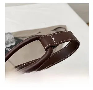 Detail of dark brown faux leather shoulder strap with white contrast stitching and soft texture