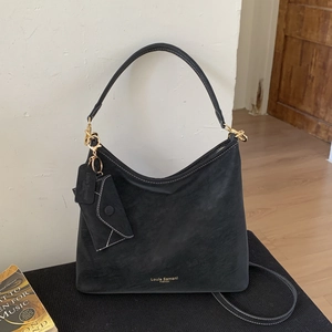 Close-up of black suede hobo bag with contrast stitching and gold logo detail