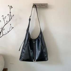 Detail of black PU leather tote bag with white contrast stitching and silver metal buckle