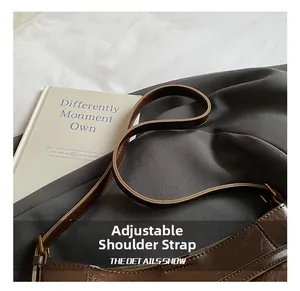 Détail de la bandoulière réglable et du cuir texturé brillant du sac marron