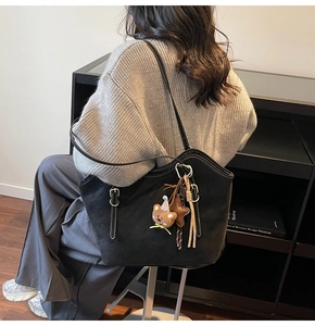Detail of black tote bag with white contrast stitching and cute charms on a model