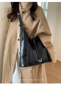 Detail of black leather hobo bag with white contrast stitching and silver ring accent