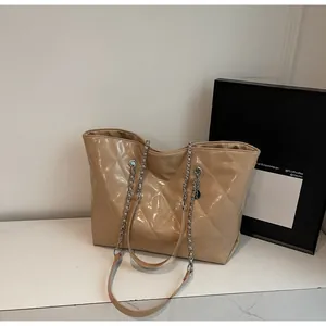 Close-up of light brown quilted patent leather tote bag with silver chain strap details