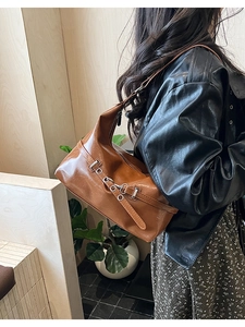 Close-up of caramel brown leather tote bag with silver buckle and adjustable shoulder strap
