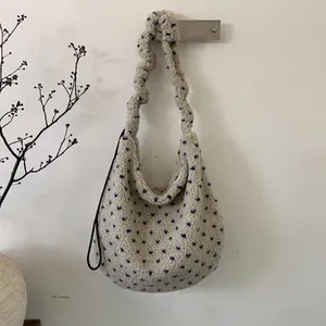Dettaglio della borsa tote in peluche beige a pois blu con tracolla arricciata di design