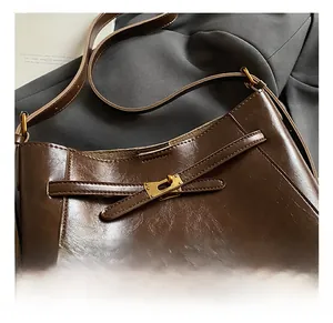 Détail de la texture cuir marron foncé avec fermoir rotatif doré emblématique