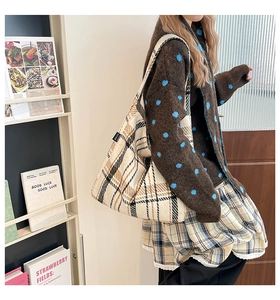 Detail of checkered tote bag with brand label shown in a cozy lifestyle setting