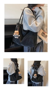 Close-up of black tote bag with a striped teddy bear keychain and matte leather finish