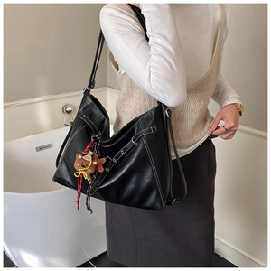 Detail of black tote bag with white stitching and cute brown bear charm accessory