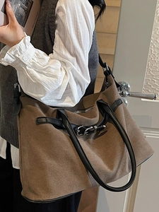 Brown large capacity tote bag with black handles shown in a casual lifestyle indoor setting