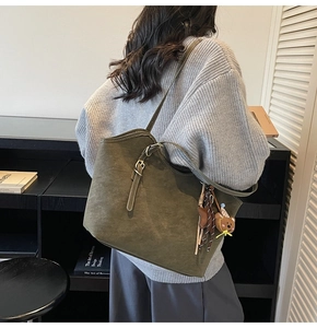 Olive green suede tote bag with brown bear charm shown on model's shoulder for a retro look