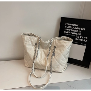 Detail of quilted beige leather tote bag with silver chain strap on white platform