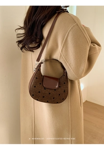 Sac croissant en tissu à pois et cuir marron porté par un mannequin en manteau beige