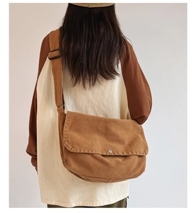 Brown canvas messenger bag detail with silver button and adjustable wide shoulder strap
