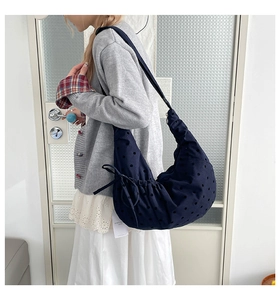 Gros plan du sac croissant bleu marine avec pois ajourés et cordon de serrage