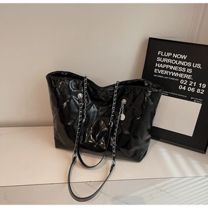Close-up of black quilted tote bag with glossy leather texture and silver chain strap