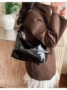 Detail of glossy black patent leather shoulder bag with silver buckle and metallic finish