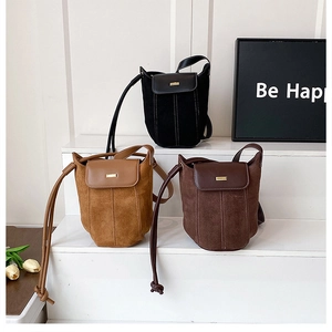 Three minimalist bucket bags in black, caramel, and coffee brown with gold hardware detail