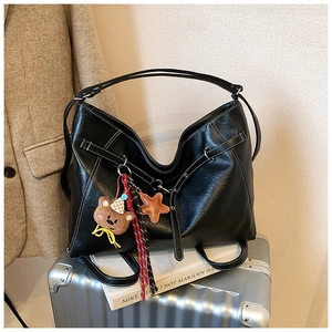 Detail of black leather hobo tote bag with white contrast stitching and cute charms